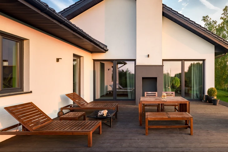 Terrasse extérieure moderne avec mobilier en teck : chaises longues, table et bancs sur plancher composite
