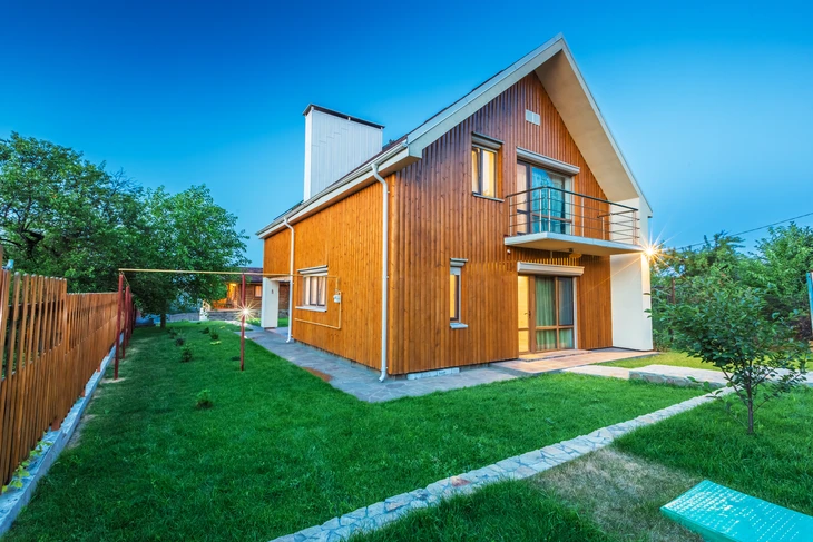 Maison individuelle moderne à ossature bois avec bardage vertical en lames de bois naturel, façade bicolore orange et blanche