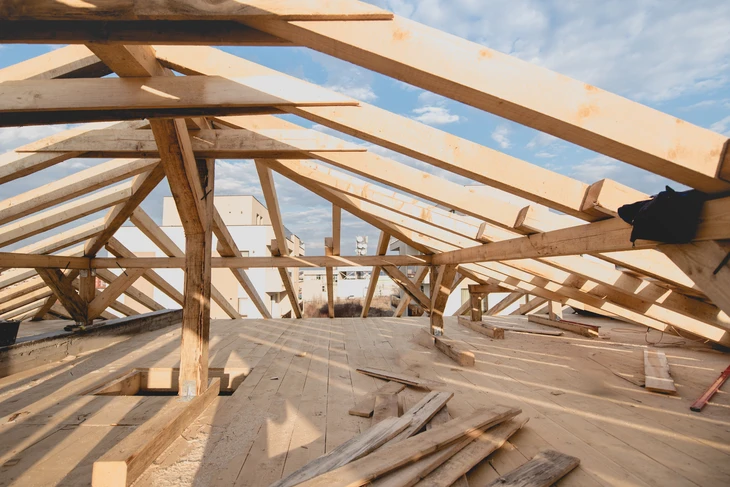 Chantier de construction d'une charpente en bois massif sous ciel bleu