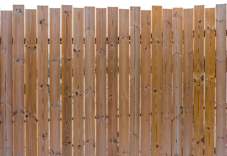 Clôture extérieure en bois naturel composée de planches verticales de différentes hauteurs créant un effet irrégulier