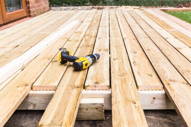 Terrasse extérieure en construction avec planches de bois naturel posées sur solives
