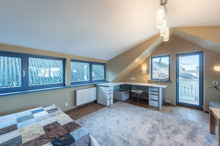 Lumineux et spacieux, le grenier de la maison dispose d'un intérieur confortable, d'un agencement de bureau contemporain et d'une grande lumière naturelle grâce à de grandes fenêtres