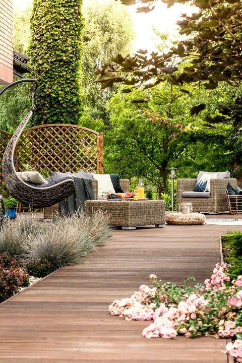 Terrasse extérieure aménagée avec salon de jardin en résine tressée, fauteuil suspendu en rotin, table basse rectangulaire