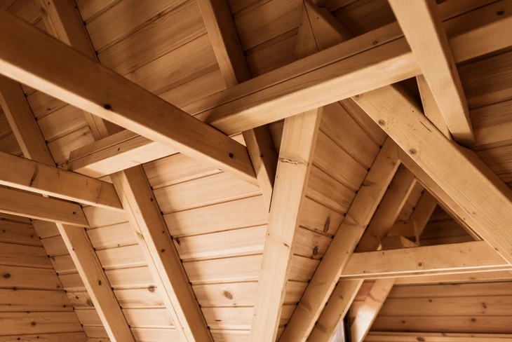 Intérieur d'une charpente en bois massif avec poutres et chevrons apparents