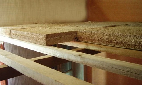 Matériau isolant en fibres naturelles beiges posé sur surface bois