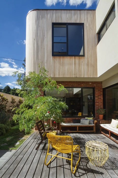 Terrasse extérieure d'une maison contemporaine avec mobilier de jardin jaune sur plancher bois