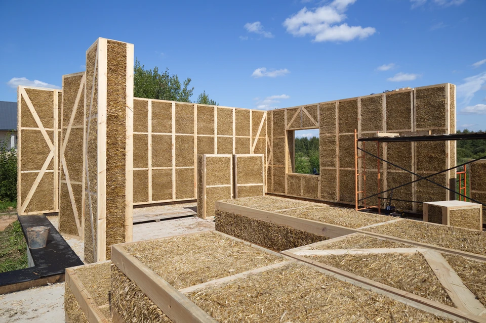 Construction d'une maison écologique en ossature bois avec isolation paille sur chantier extérieur