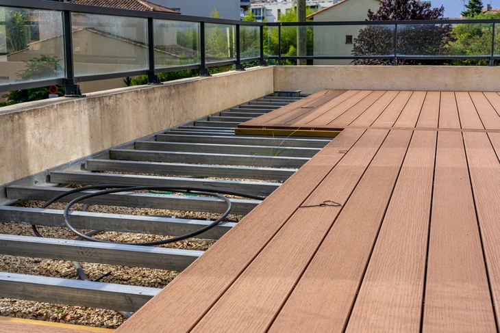 Terrasse extérieure en cours d'aménagement avec pose de lames de bois exotique sur structure métallique
