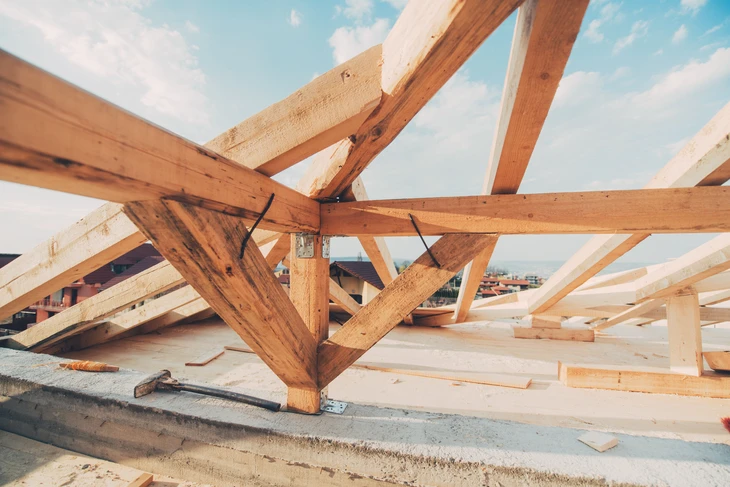Chantier de construction en extérieur avec charpente en bois massif en cours d'assemblage