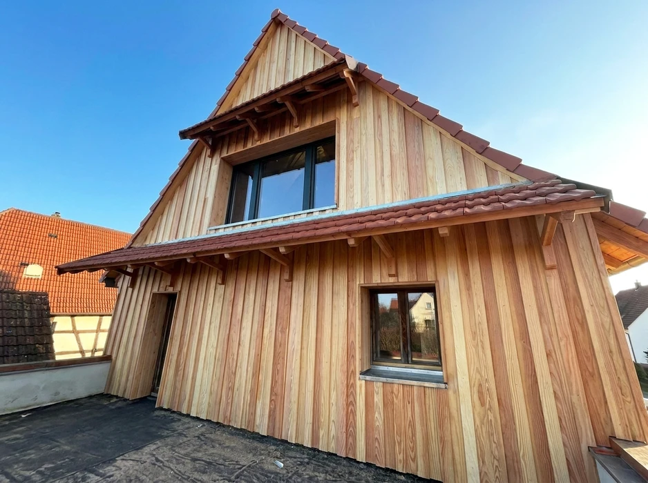 Maison neuve à ossature bois avec bardage vertical en lames de douglas non traité, façade pignon