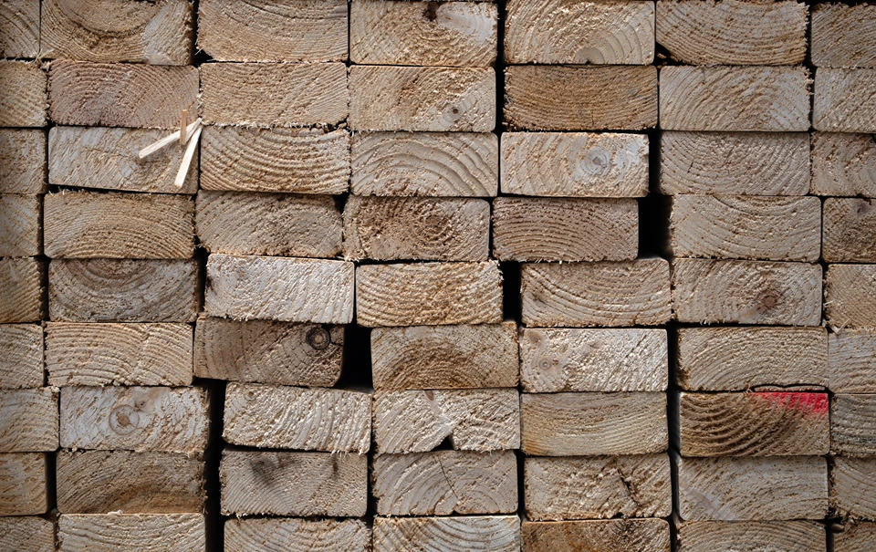 Extérieur, pile de planches en bois brut empilées horizontalement, essence claire type pin ou sapin