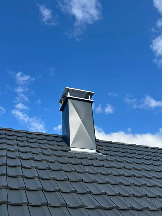 Charpentier en combinaison de travail, agenouillé sur un toit en cours de construction, utilisant un cloueur pneumatique