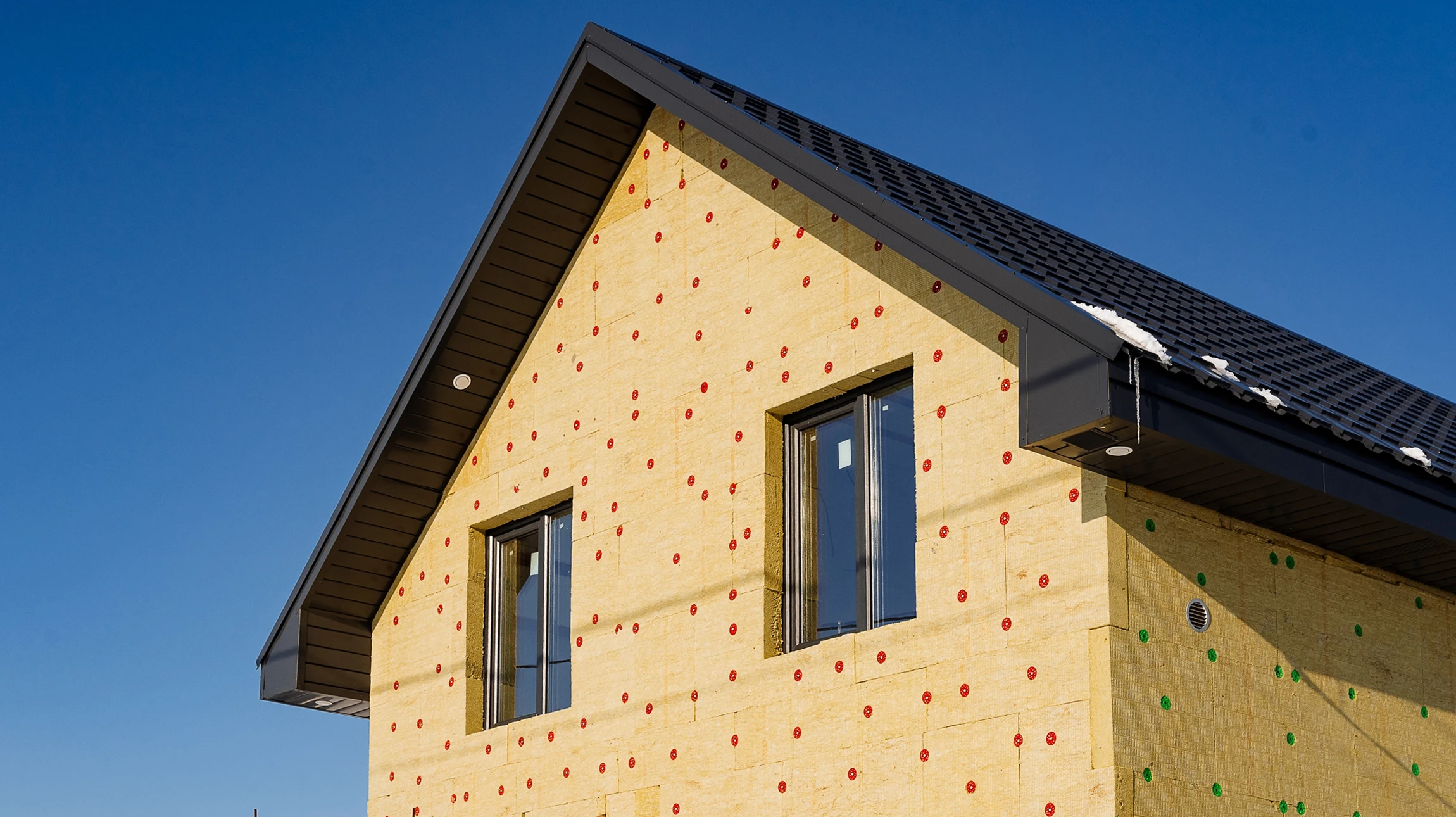 Ouvrier appliquant un enduit de façade sur mur extérieur avec taloche, travaillant en plein air sous lumière naturelle